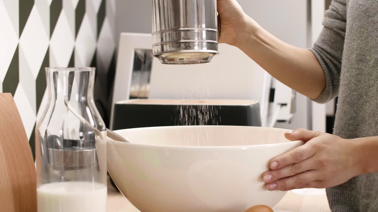 Donna che setaccia la farina in cucina