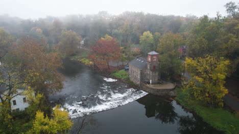 Historische-Mühle-Am-Fluss,-Drohnenaufnahme,-Nebliger-Herbstmorgen,-Erstaunliche-Blätter