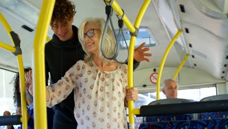 male commuter helping mature commuter while travelling in bus 4k