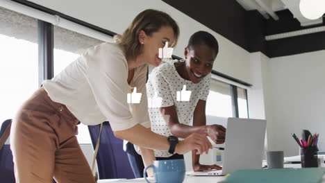 animation of media icons over diverse female colleagues discussing work in office