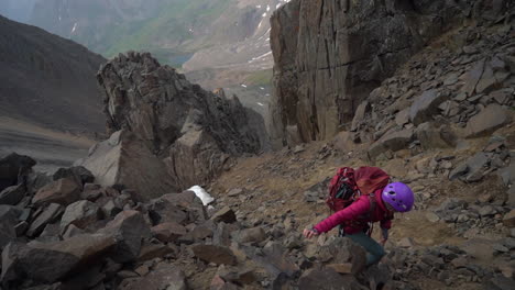 female climber on difficult steep rocky mountain hill climbing on mount sneffels 14er, colorado usa, full frame