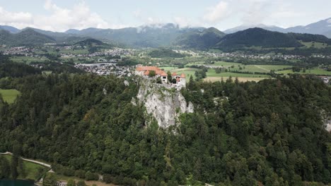 Castillo-En-Una-Colina-Junto-A-Un-Lago-Con-Montañas-Al-Fondo