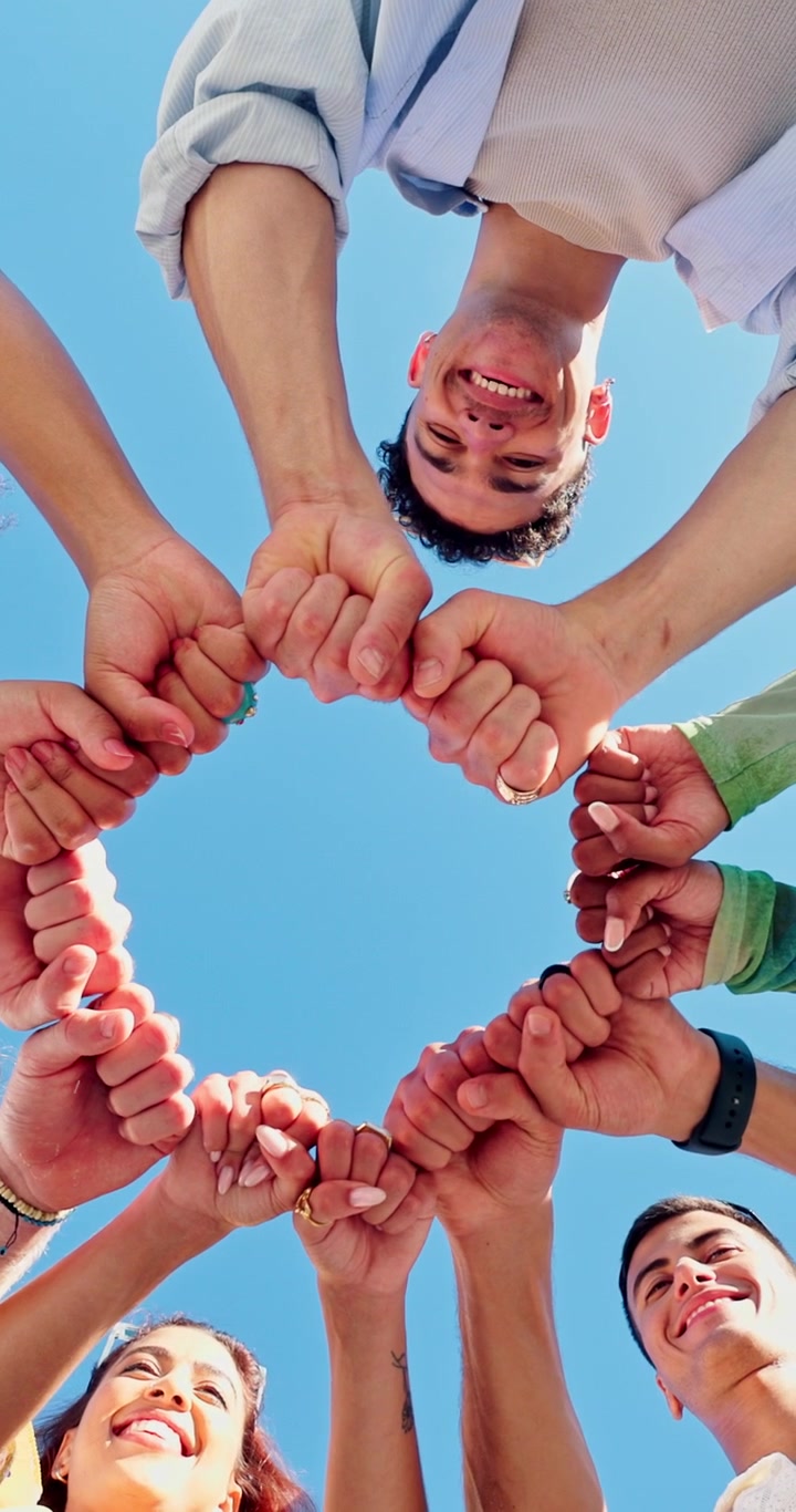Gruppo eterogeneo di amici che uniscono i pugni in segno di unità