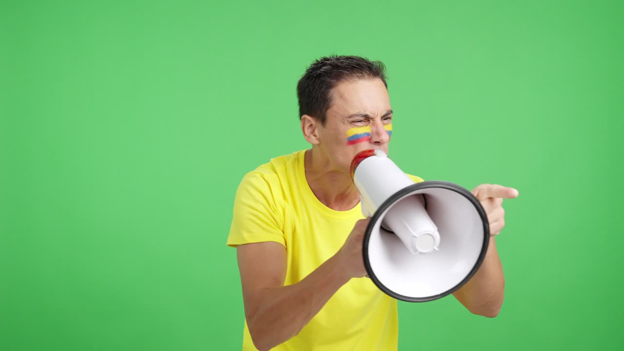 Excited man with colombian flag on face using a megaphone