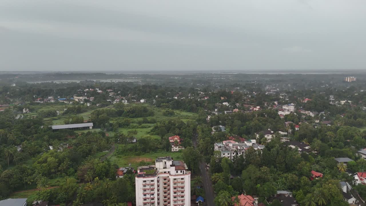 Foto dall'alto di case nascoste sotto una fitta chioma di alberi, che enfatizza l'ambiente verde del Kerala