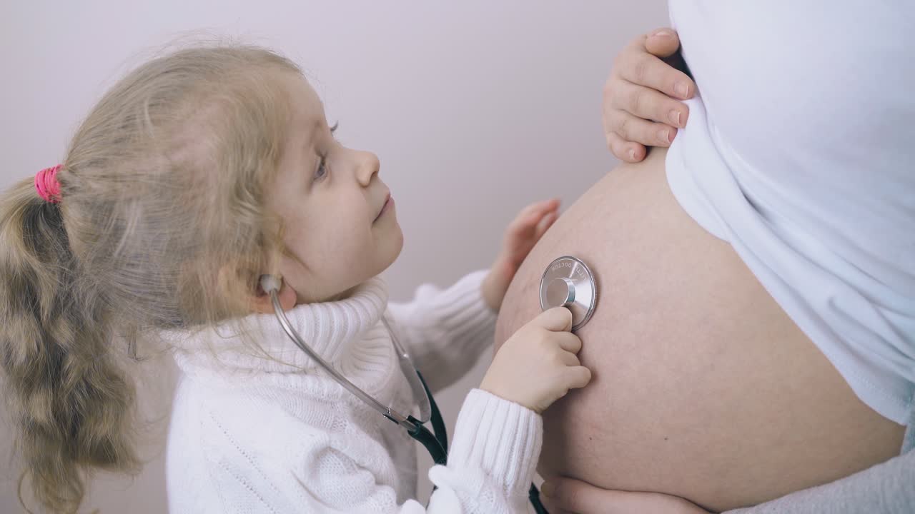 il bambino ascolta il battito cardiaco del bambino nella pancia della madre