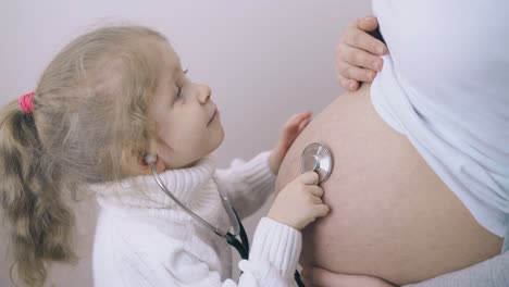 Un-Niño-Pequeño-Escucha-Los-Latidos-Del-Corazón-Del-Bebé-En-El-Estómago-De-La-Madre.