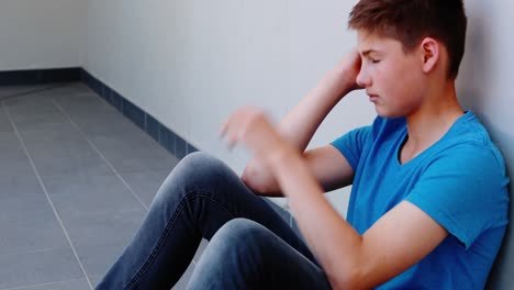 Sad-schoolboy-sitting-in-corridor