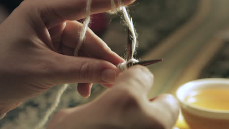 Hands-carefully-stitch-yarn-with-knitting-needles,-close-up