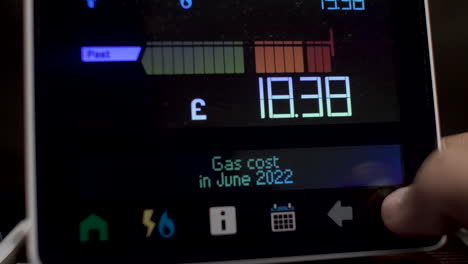 close up of finger pressing touchscreen display of uk energy smart meter to check cost of gas usage by month in 2022