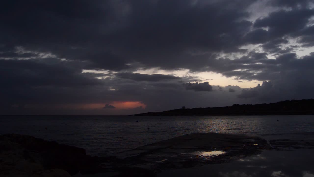 Ripresa in tempo reale dell'alba a Qawra, Malta, giorno di pioggia con nuvole nere e scure