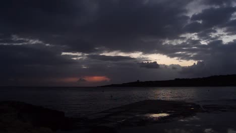 Echtzeitaufnahme-Des-Sonnenaufgangs-In-Qawra,-Malta,-Regnerischer-Tag,-Dunkle-Schwarze-Wolken