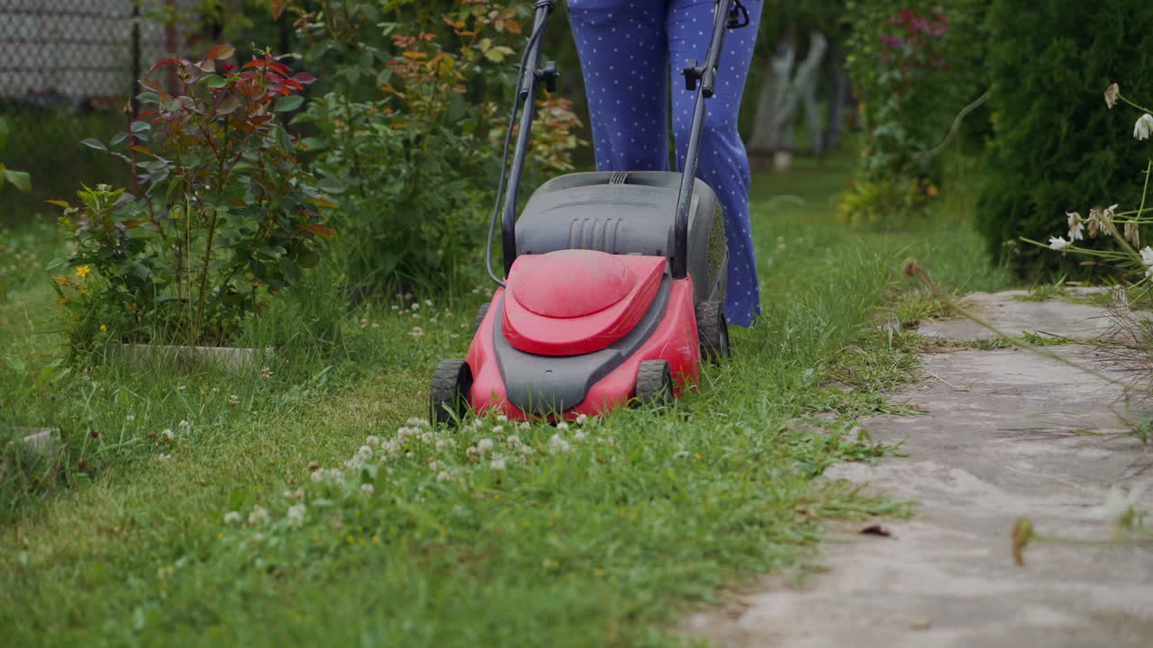 Woman running with a lawn mower in the garden. Close-up