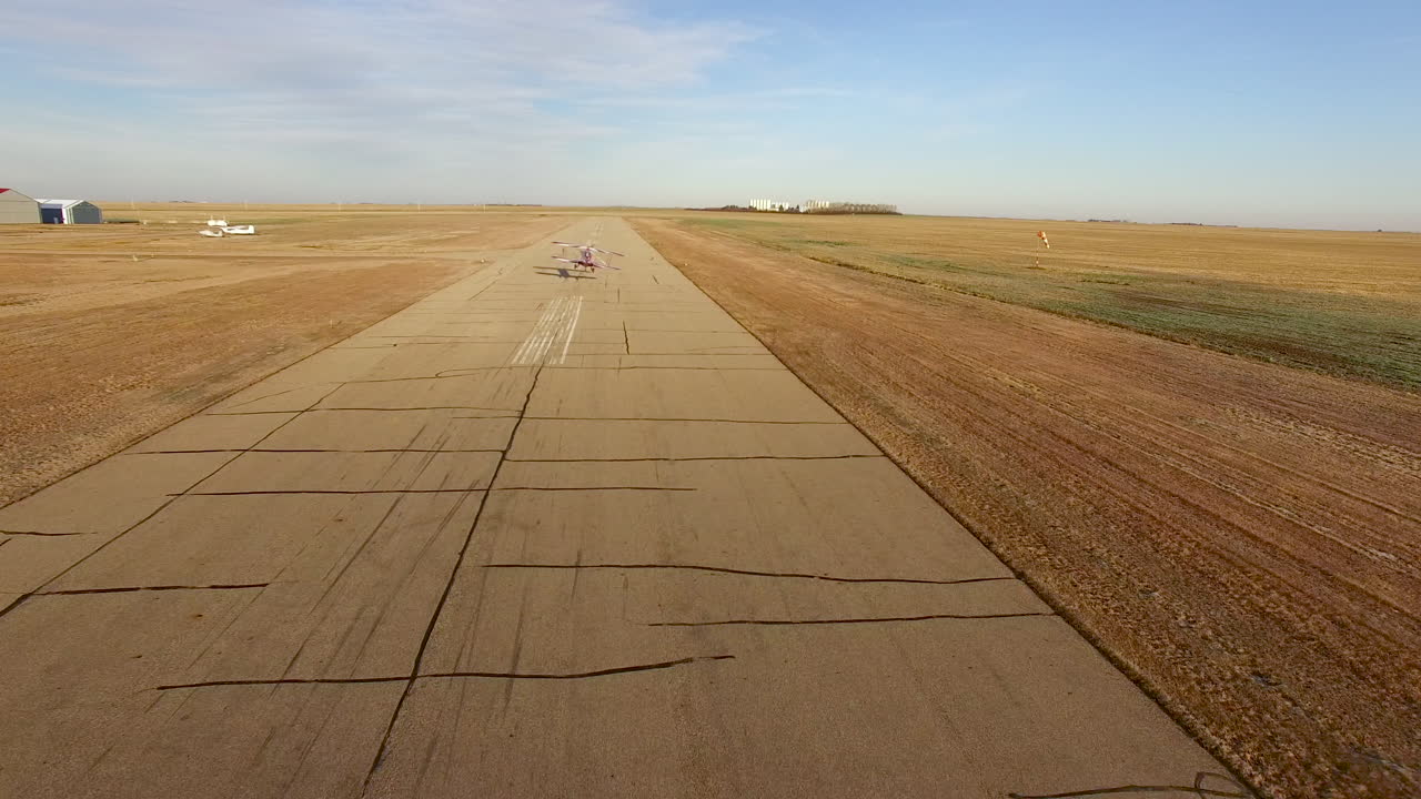 биплан воздушного шоу pitts s2b взлетает по небольшой взлетно-посадочной полосе, как видно с дрона