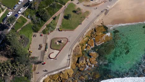 top down view of saltwater rock pool and foamy waves on sandy shore of bronte beach in sydney, australia - aerial drone shot