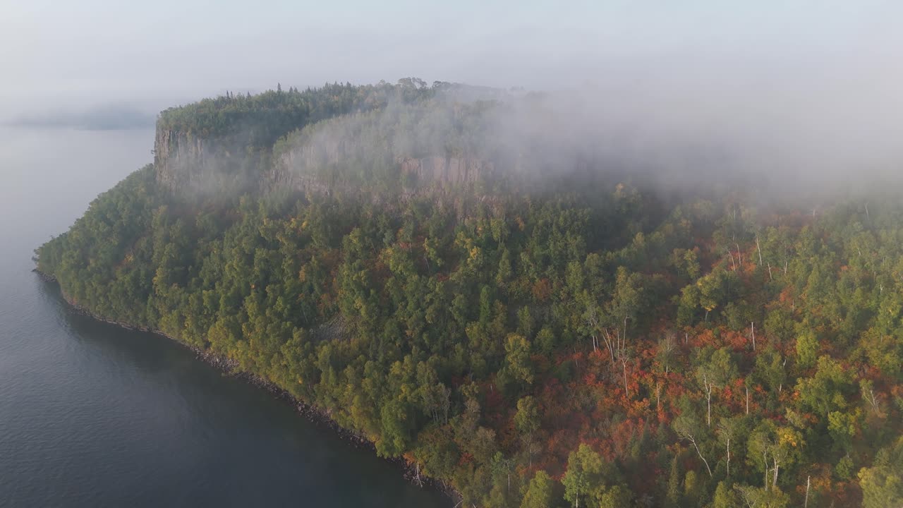 The calm, fog-laden morning along Lake Superior unveils dramatic cliffs and vibrant fall foliage on Ontario’s remote northern shore