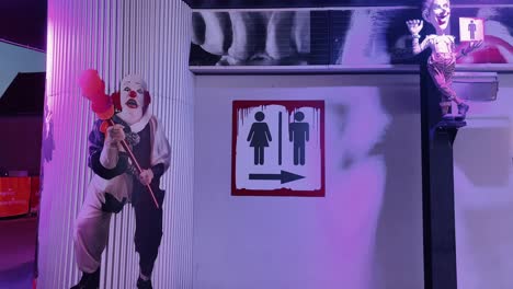 spooky clown art and restroom sign with eerie lighting in a themed setting