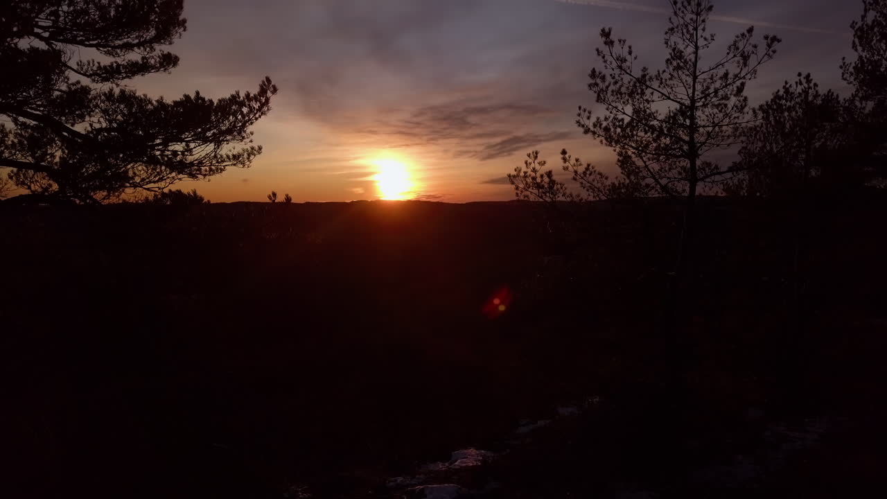 aéreo, ascendente, disparo de drone, detrás del bosque, mirando la puesta de sol, en la colina dyblemyrheia, en un día soleado de otoño, en lillesand, aust-agder, sur de noruega