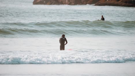 un surfista caminando hacia el surf break en tofino, columbia británica