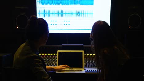 ingenieros de audio usando computadora portátil mientras mezclan sonido