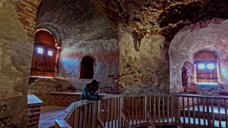 woman taking pictures inside castle of bauska with closed windows and walkway