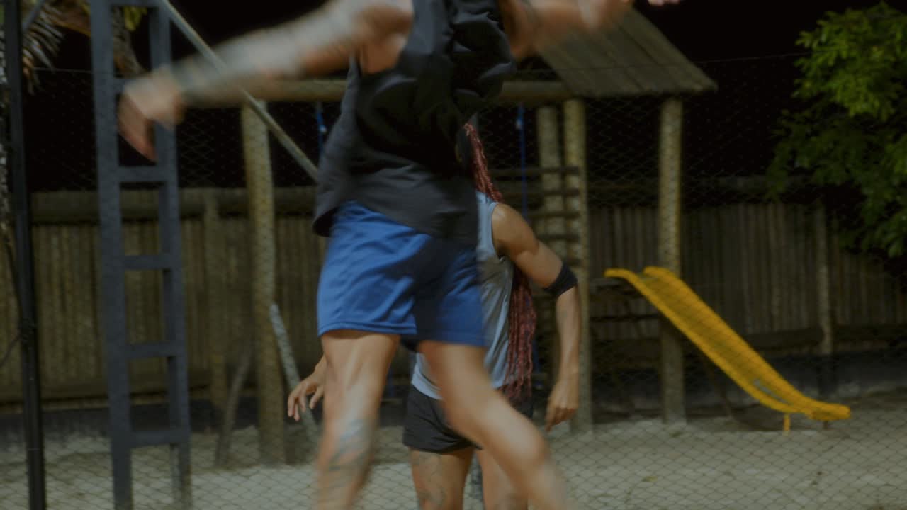 Two Men Playing an Active Sport on a Sandy Court at Night