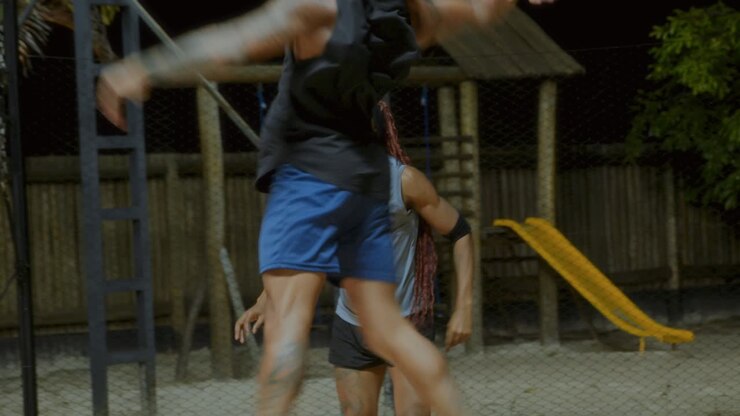 Two Men Playing an Active Sport on a Sandy Court at Night