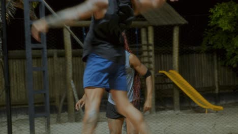 Two Men Playing an Active Sport on a Sandy Court at Night