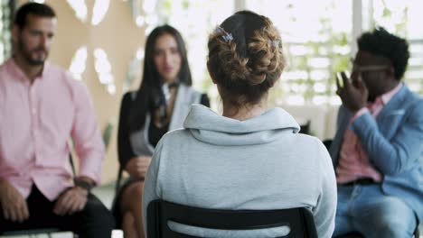 vista posterior de una mujer joven con trenza sentada en una silla