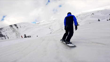 following a male snowboarder going down the slope. winter sport activity in the mountains.
