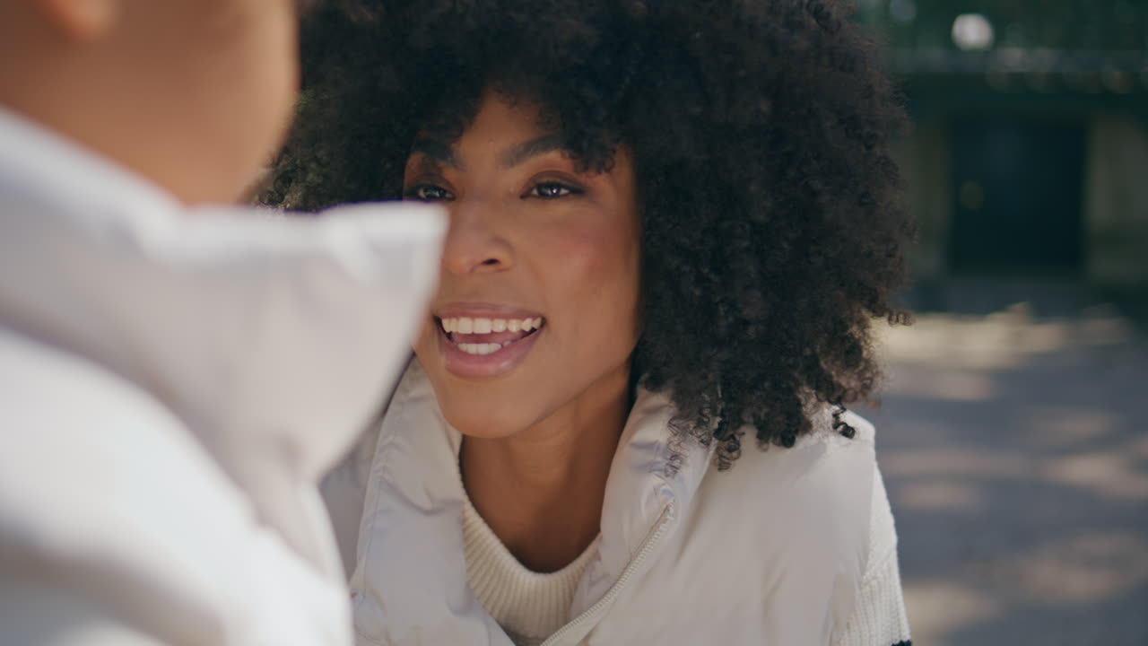 madre hablando con su hija pequeña en cuclillas en el parque de cerca.