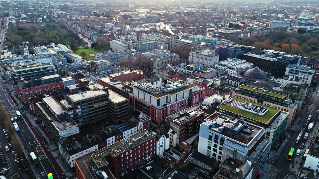 Dronebillede i fugleperspektiv af det irske hovedstadsområde Dublin med travle gader fulde af trafik og turister, der går rundt i de lysende gader ved solopgang om vinteren med irsk arkitektur