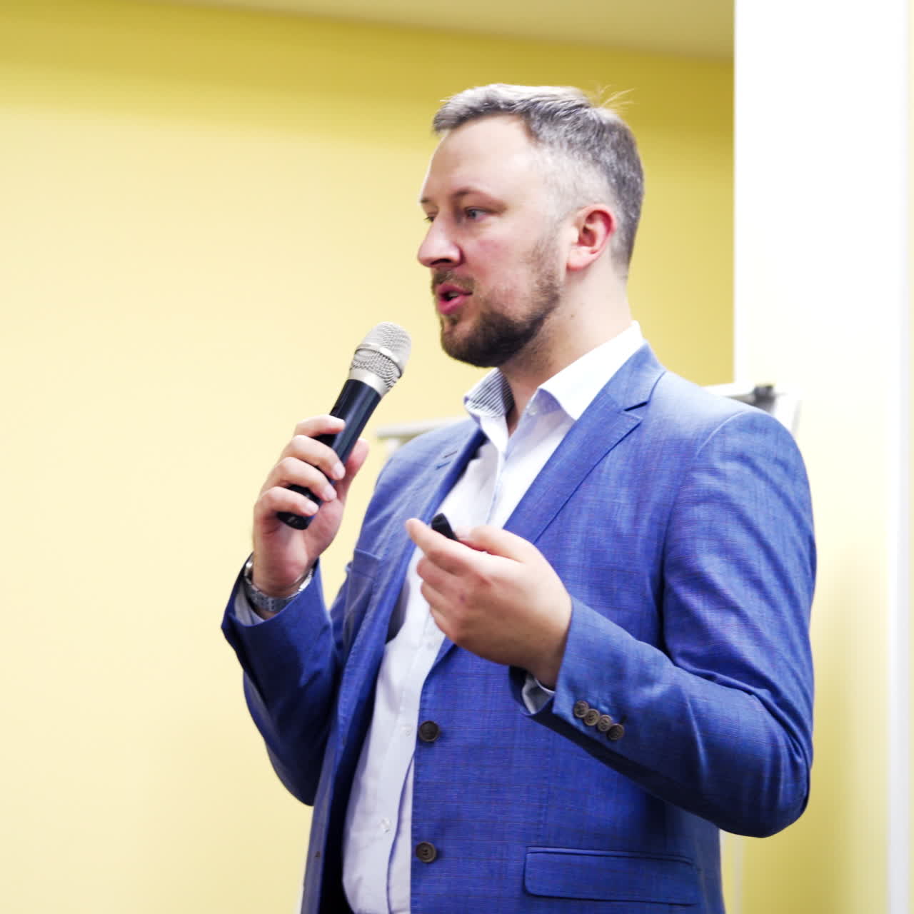 Businessman in elegant suit explaining the lecture in the conference room. Handsome male speaker with the microphone. Professional ideas, politics or economy,