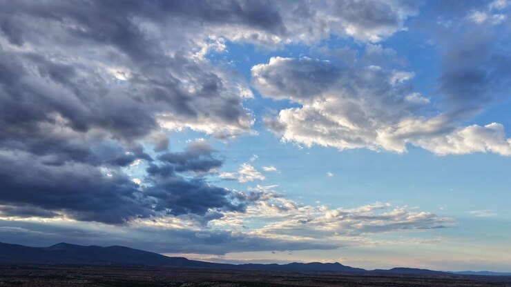 Timelapse 4K de dron captura nubes grises y plateadas sobre un paisaje del suroeste de mesetas y montañas al anochecer. El atardecer trae un clima tormentoso cambiante y luz dramática al terreno del desierto alto