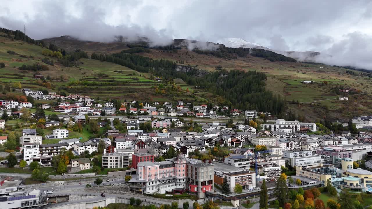 Scuol, Sveitsi, ilmakuva viehättävästä kaupungista rehevien vihreiden kukkuloiden ja vuoristomaiseman ympäröimänä.