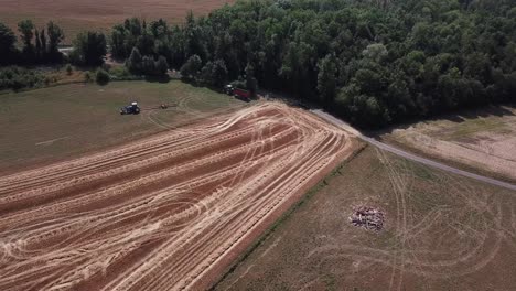 A-cinematic-4K-drone-shot-of-two-tractors-working-on-a-field-in-France,-showcasing-agriculture-with-an-epic-view-and-dramatic-dust