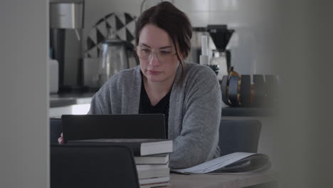 caucasian woman works remotely or studies at home with laptop and books