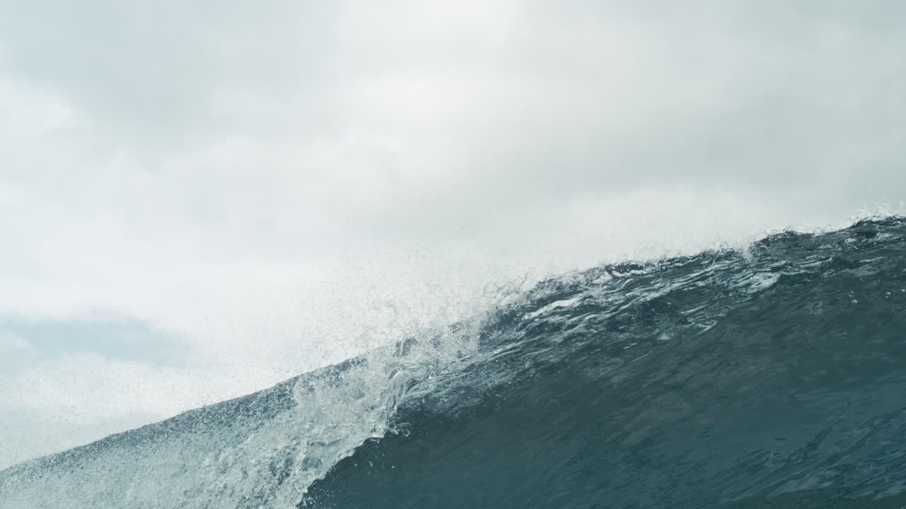 Gentle crashing lip forming offshore in calm sea under flat light and distant haze