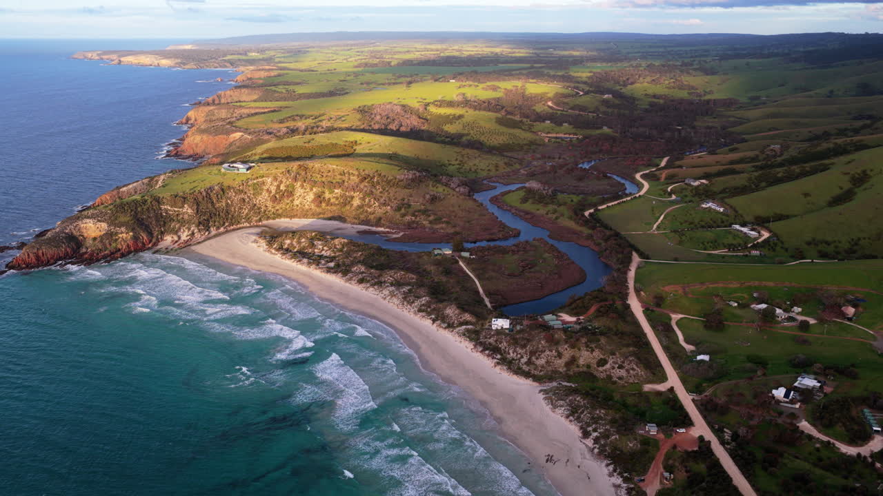 Ampia veduta aerea all'ora d'oro su Snelling Beach e l'estuario del Middle River, con dolci colline verdi e il rigoglioso paesaggio costiero di Kangaroo Island, in Australia, in lontananza