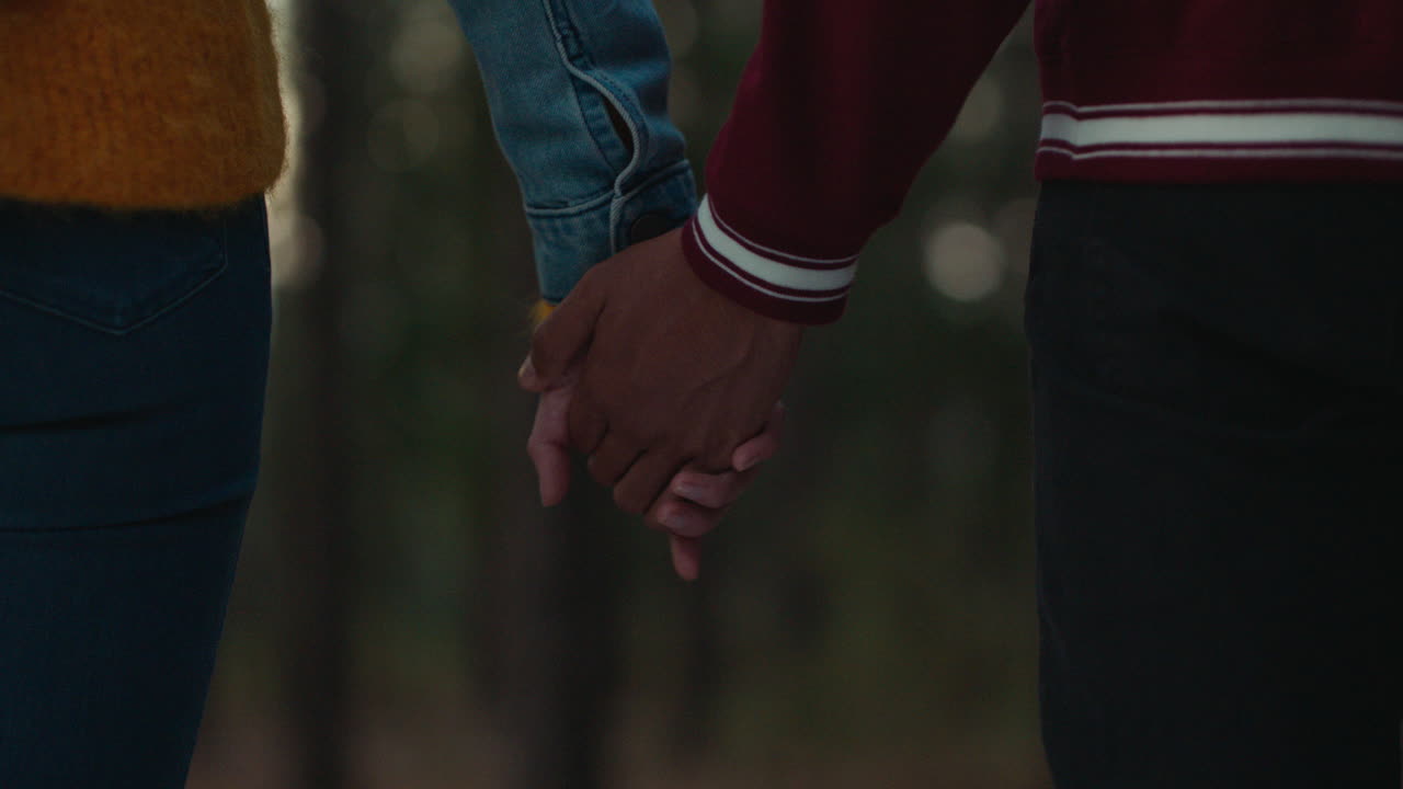 teenage couple holding hands in forest at sunset boyfriend playfully holds girlfriends pinky finger sharing romantic connection in woods happy young lovers