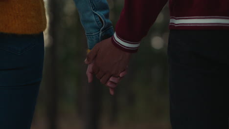 teenage couple holding hands in forest at sunset boyfriend playfully holds girlfriends pinky finger sharing romantic connection in woods happy young lovers