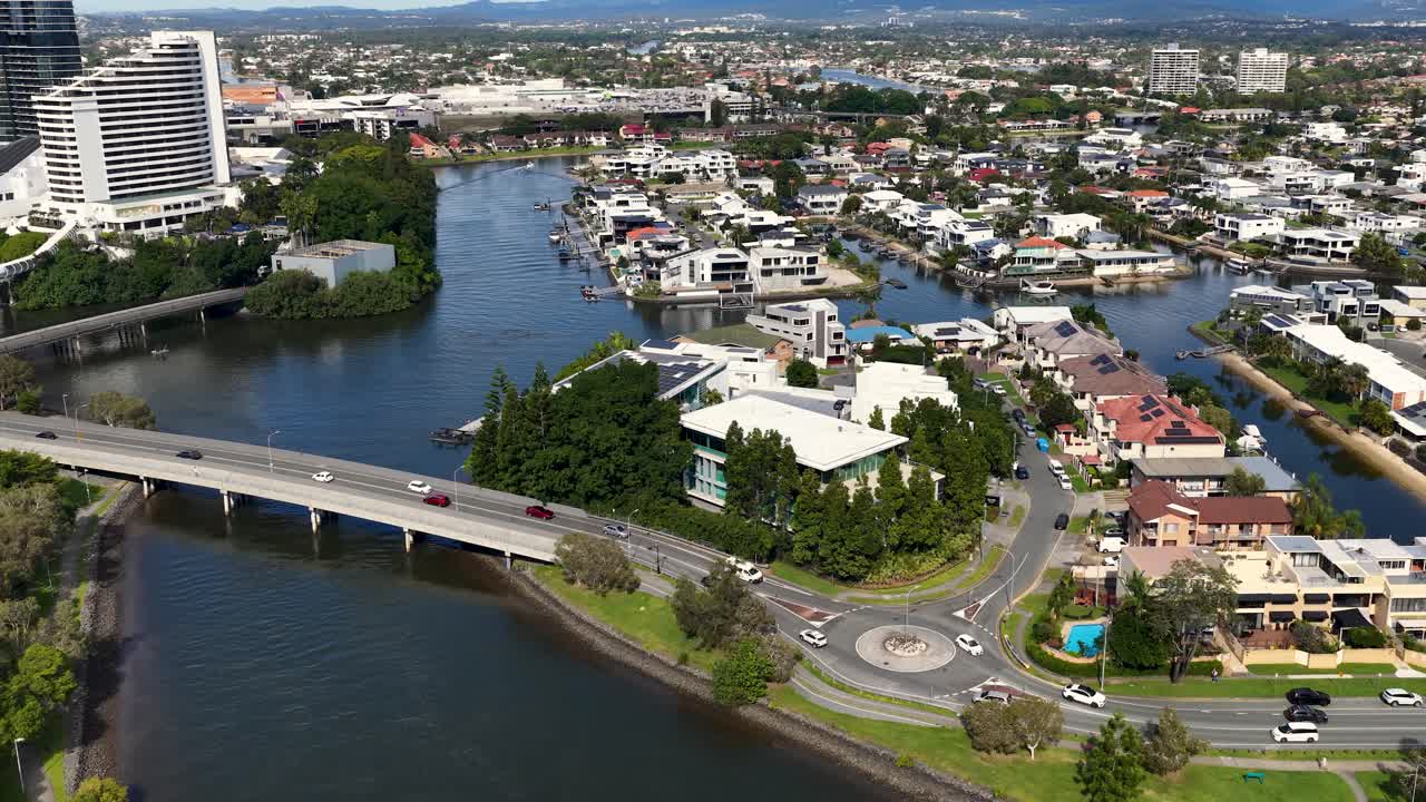 Aerial timelapse showcasing urban landscape, featuring a bridge over the Nerang River and surrounding residential areas under clear skies