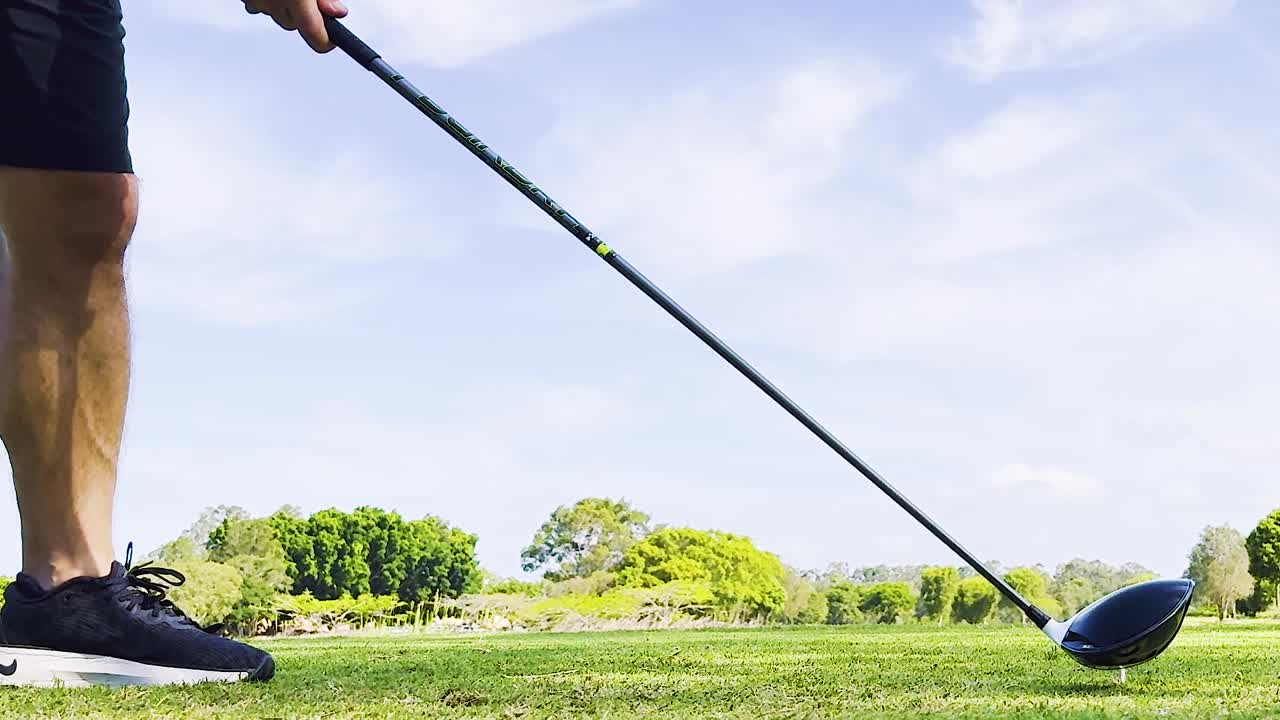 Close-up of golfer's legs and club preparing to hit a ball on a sunny day.