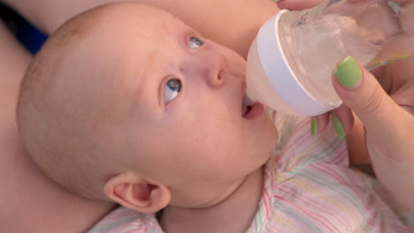 mom giving baby to drink water from the bottle