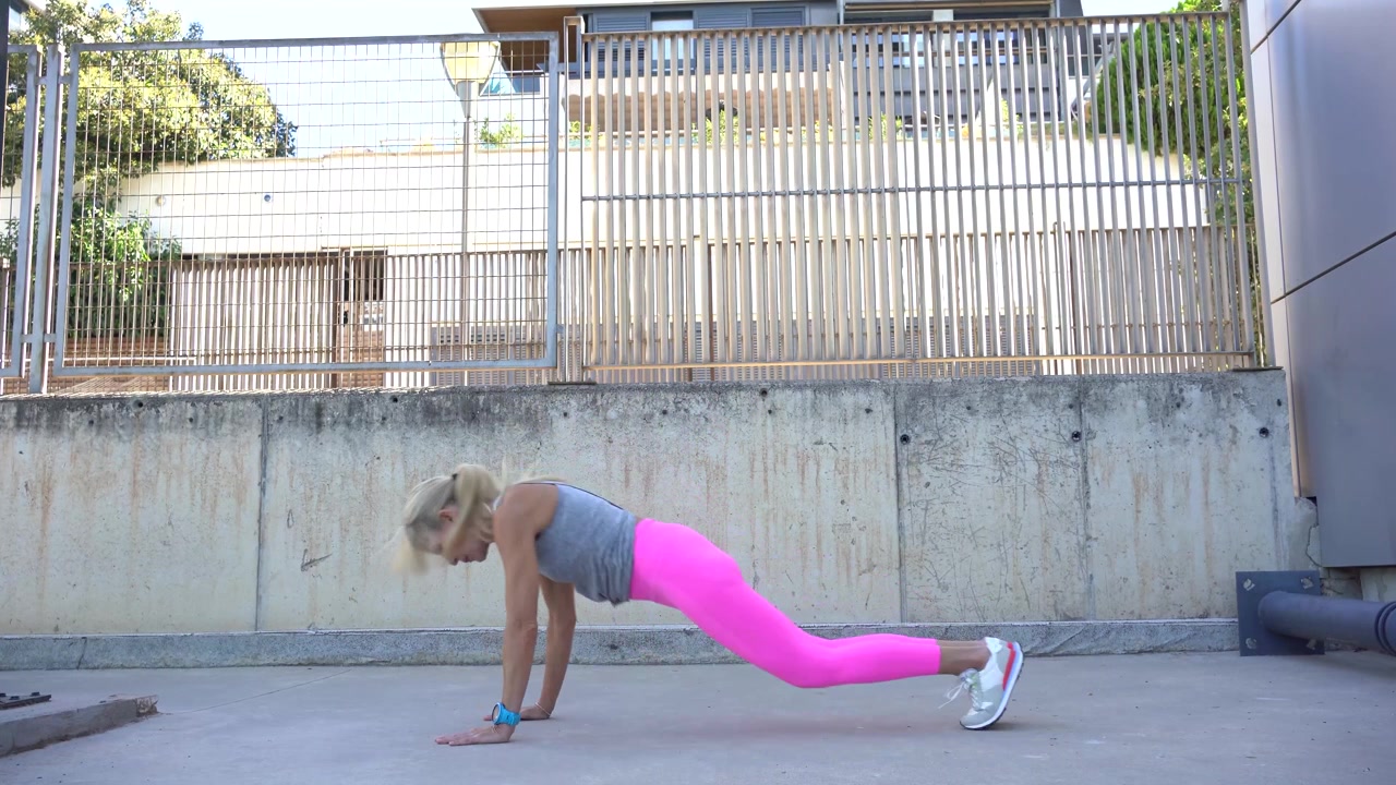 Donna in forma che esegue plank e salti durante l'allenamento.