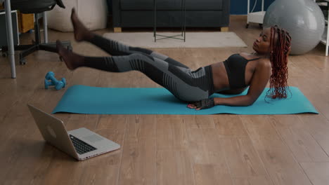 Athletic fit woman doing scissors exercise sitting on yoga map