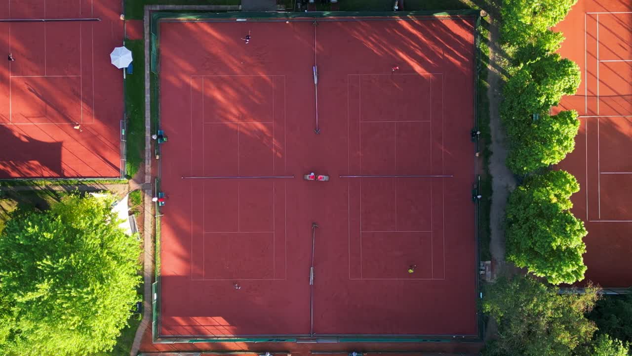 Persone che giocano una partita di tennis su campi in terra battuta in una giornata di sole a Berlino, Germania. Maestosa vista aerea ripresa da drone con telecamera puntata verso il basso.