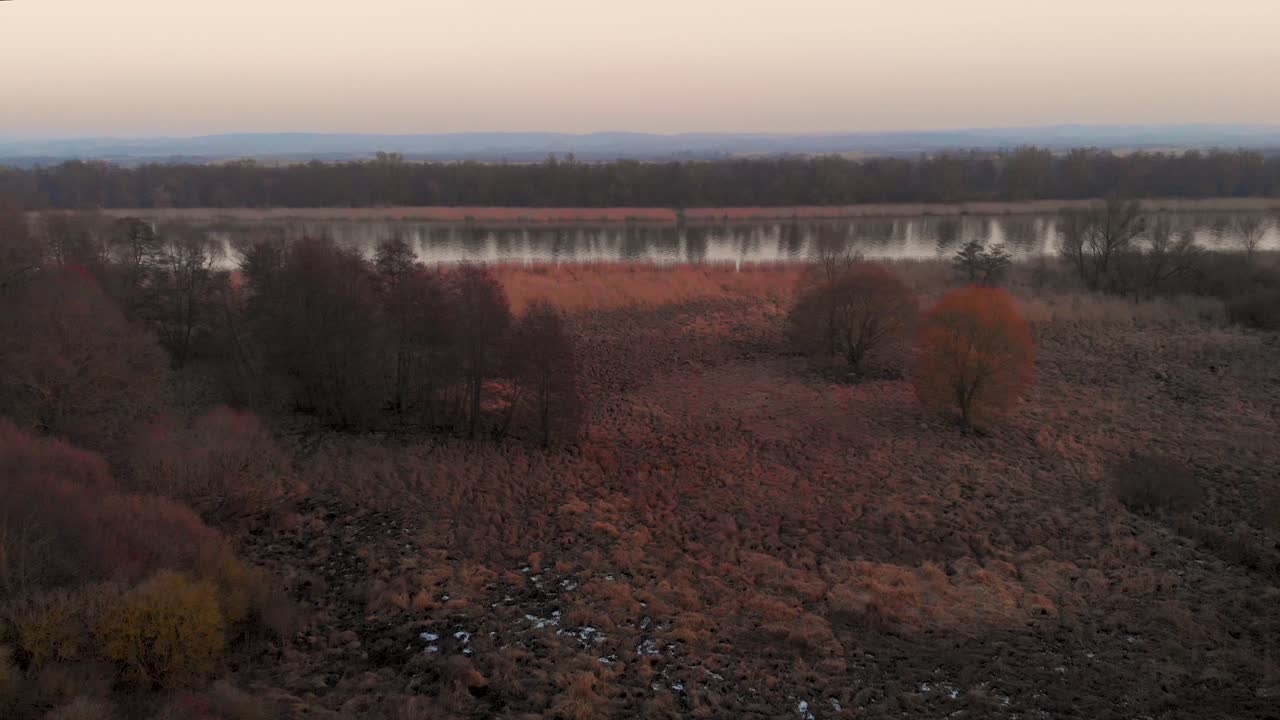 drone volando sobre el paisaje rural revelando el lago al atardecer durante el otoño en polonia