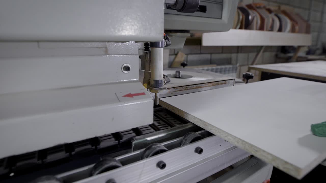 Mãos colocando painel branco na máquina para corte na oficina
