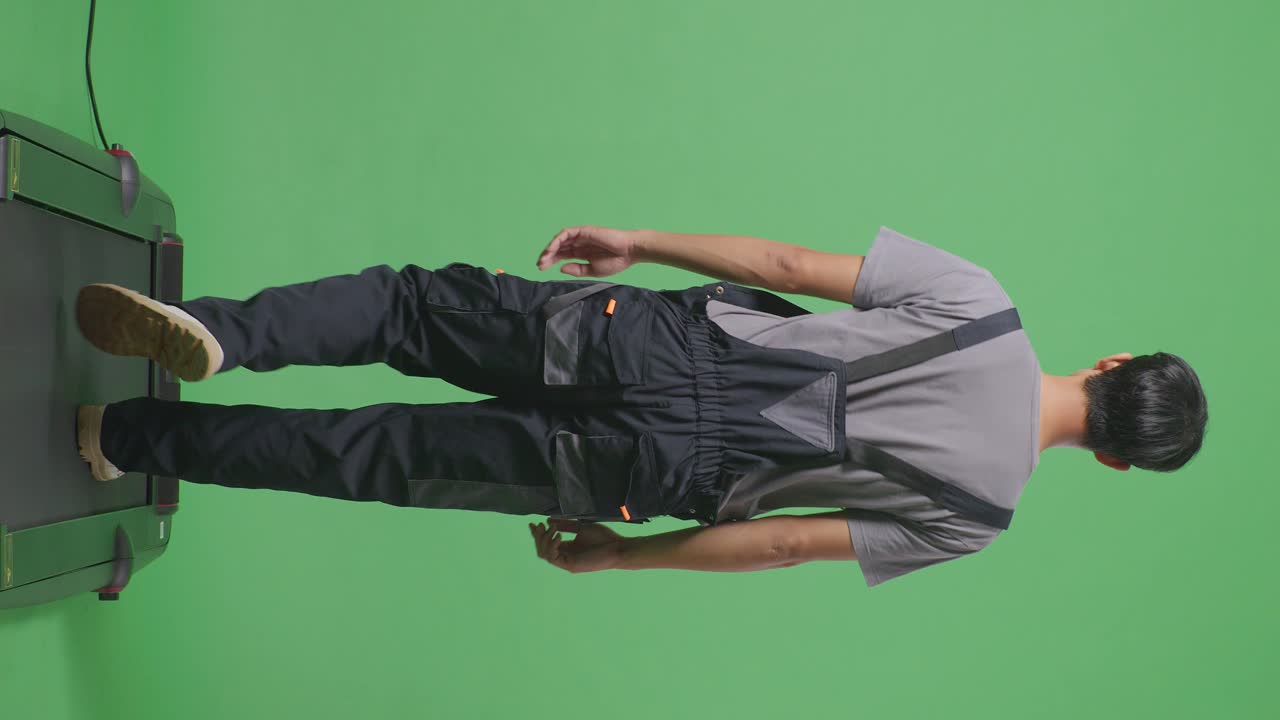 Man walking on a treadmill in coveralls, green screen background